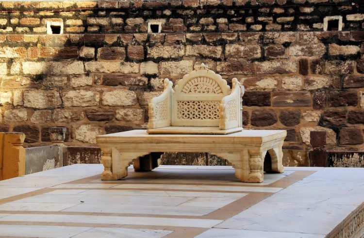 A marble Indian throne in front of a stone wall