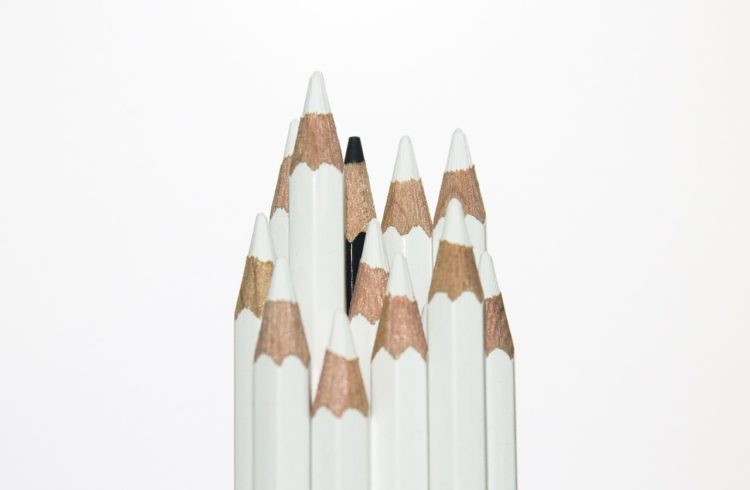 twelve pencils, all white except for one black