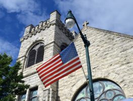 American flag waves in front of an American church
