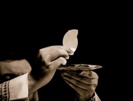 PIcture of a pastor or priest holding up the bread of eucharist