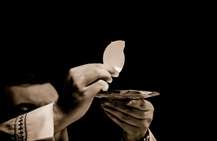 PIcture of a pastor or priest holding up the bread of eucharist