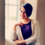 picture of Lauren Jacobs standing in front of a window with a purple dress on