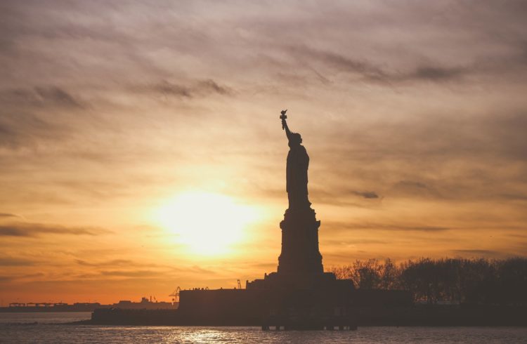 Suset behind sihloutted picture of Statue of Liberty